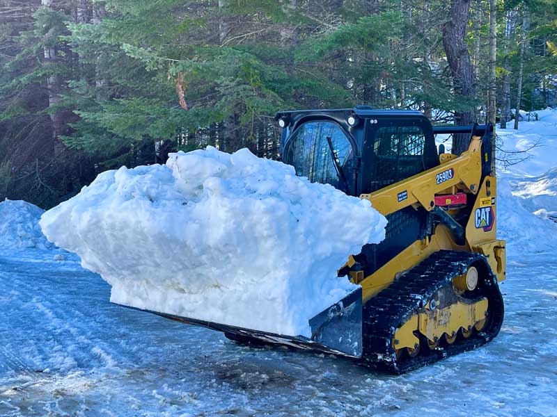 Snow Plow with large amount of snow with forest in the background