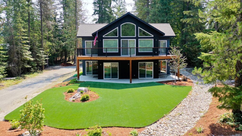 backyard area with a black house and a green turf lawn